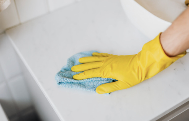 Someone cleaning a surface with a blue microfiber cloth.