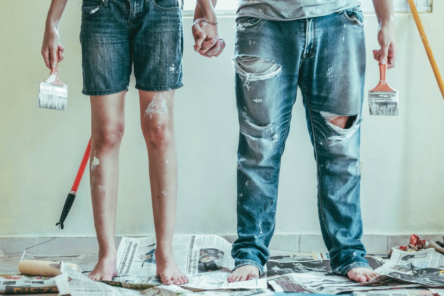 two people standing together with paintbrushes and newspaper 